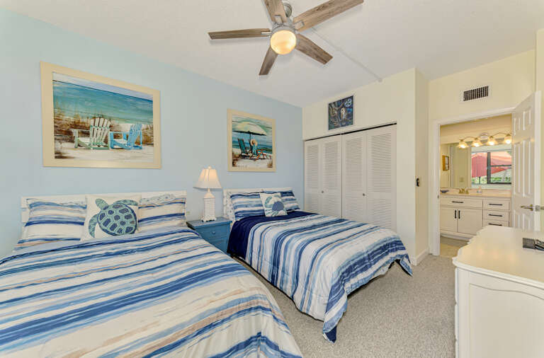 Relax in your coastal-themed twin bedroom with soft blue stripes, beach artwork, and an ensuite bathroom for comfort.