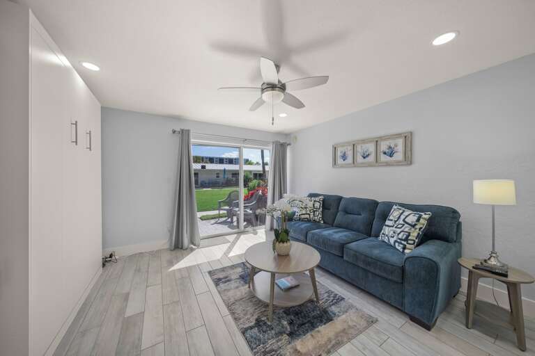 Relax in your bright living space with cozy blue sofa, ceiling fan, and direct patio access to your private yard.