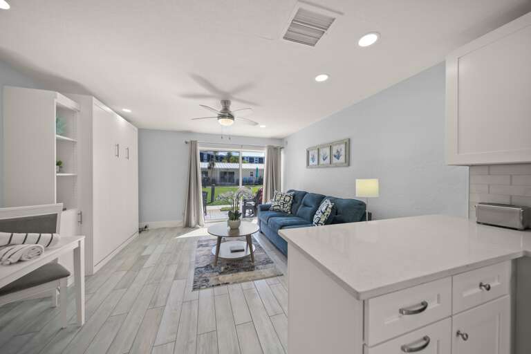Your stylish open-concept living space flows seamlessly from kitchen to lounge, featuring modern finishes and a cozy blue sofa perfect for relaxation.