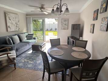 Your stylish living space flows seamlessly from comfortable seating to dining table, with garden views through sliding doors creating a bright, welcoming atmosphere.