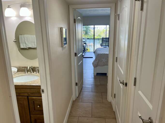 Your private hallway connects your stylish bathroom to your comfortable bedroom with balcony access and palm tree views.