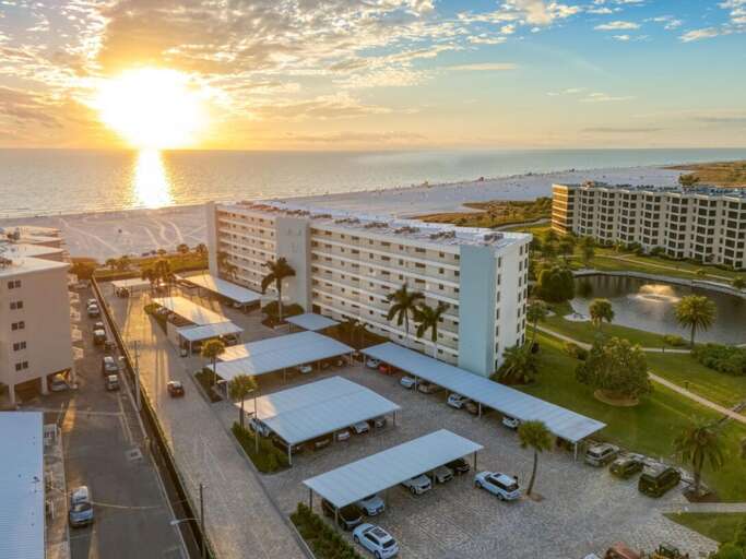 Beachfront resort property with covered parking areas and landscaped grounds, situated steps from pristine white sand beaches.