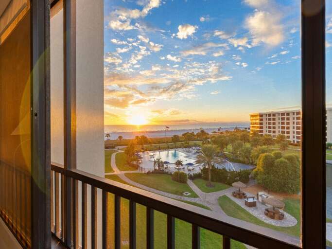 Stunning sunset views from your private balcony showcase the resort's pool and lush grounds in golden hour light.
