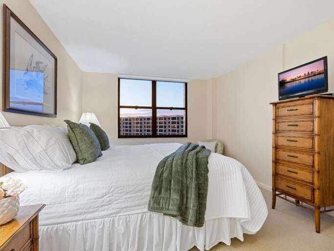 Sink into crisp white linens and soft green accents in your peaceful bedroom retreat, complete with warm wood furnishings and city views.
