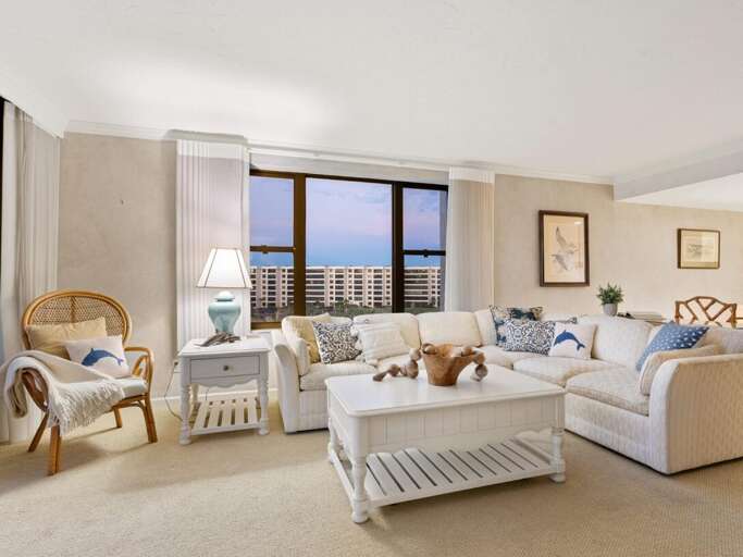 Sink into plush sofas while enjoying stunning city views through floor-to-ceiling windows in this elegantly furnished living space.