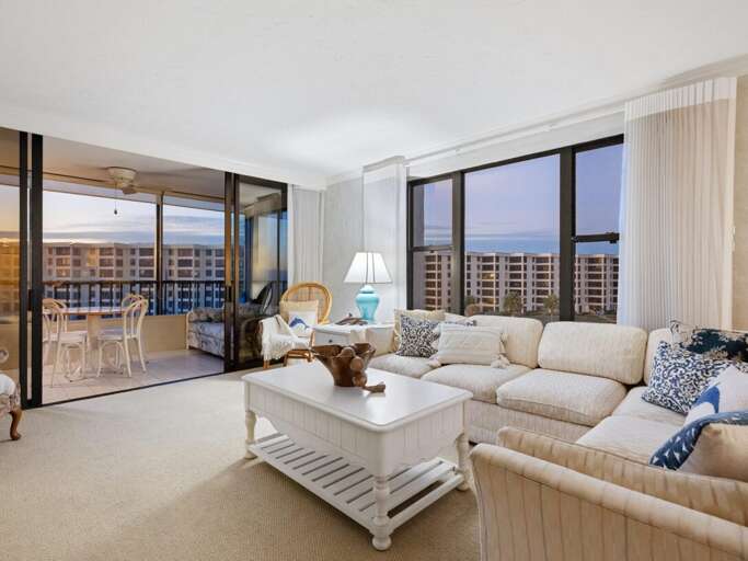 Sink into plush sofas while ocean views stretch endlessly beyond your private balcony in this bright, coastal-inspired living space.