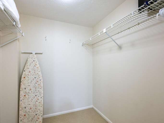 Your spacious walk-in closet features ample storage with wire shelving and a convenient ironing board for all your wardrobe needs.