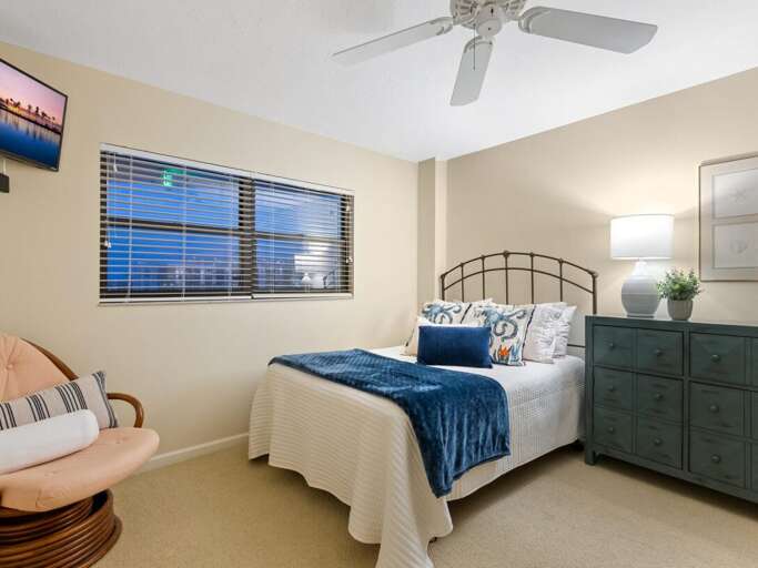 Unwind in your peaceful bedroom with coastal blues and soft linens, complete with ceiling fan for comfort.