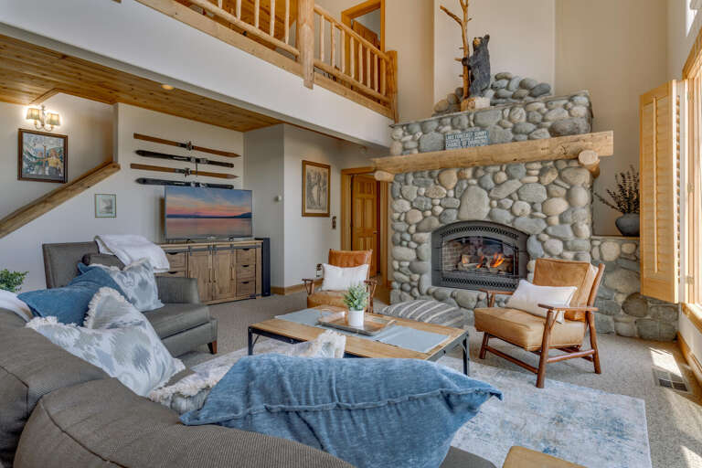 Spacious Living Area With Stone Fireplace, Soft Sofas, And Wooden Accents