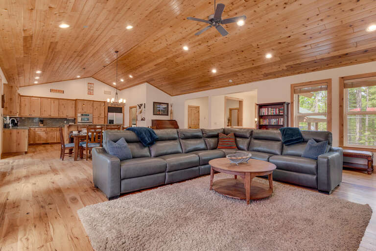 Spacious Living Area With Large Sofa, Wooden Ceiling, And Kitchen View