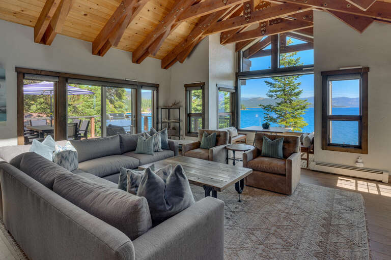 Spacious Living Room With Lake View, Large Windows, And Wooden Beams