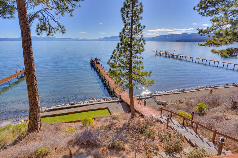 Lakeside Vista With Vibrant Trees, Descending Dock, And Deep Blue Waters