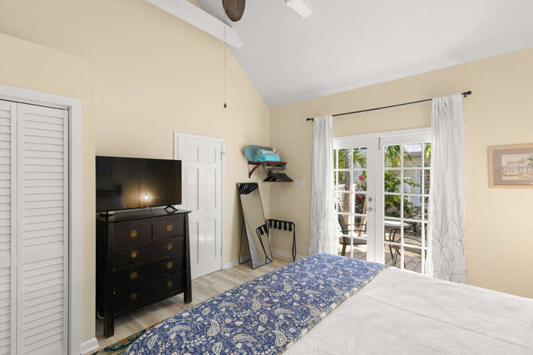 Your bright, airy bedroom opens directly onto the terrace through elegant French doors, inviting natural light and tropical breezes. The vaulted ceiling and coastal decor create a serene retreat perfect for unwinding after island adventures.