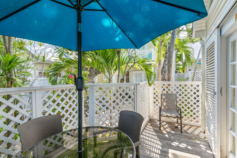 Relax on your private patio surrounded by tropical palms and sunshine. Enjoy morning coffee or evening conversation at the outdoor table beneath the bright blue umbrella in this secluded, breezy space.