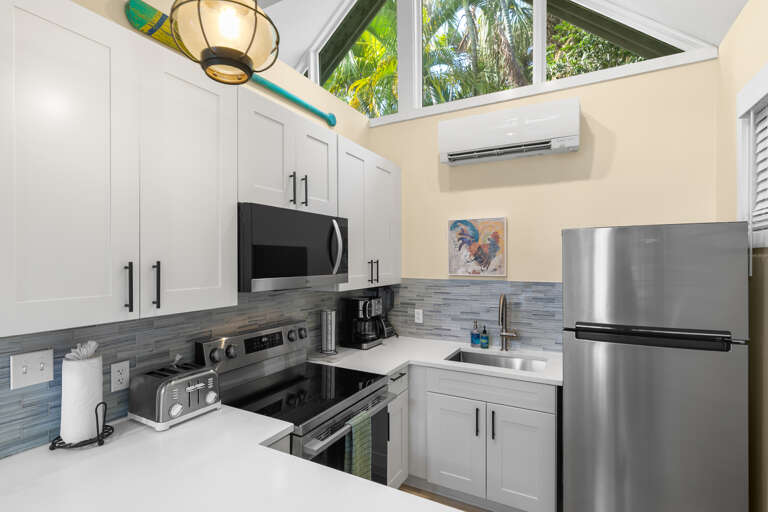 Your bright, fully equipped kitchen features stainless appliances, vaulted ceilings, and a skylight framing lush tropical palms—perfect for cooking in paradise.