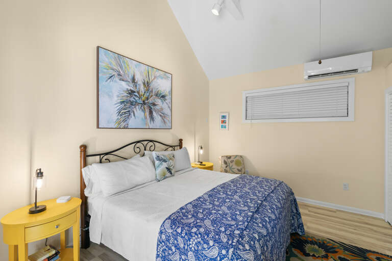 Settle into your bright and airy bedroom, where coastal charm meets comfort. The vaulted ceiling and soft yellow accents create a warm, inviting retreat perfect for restful nights.