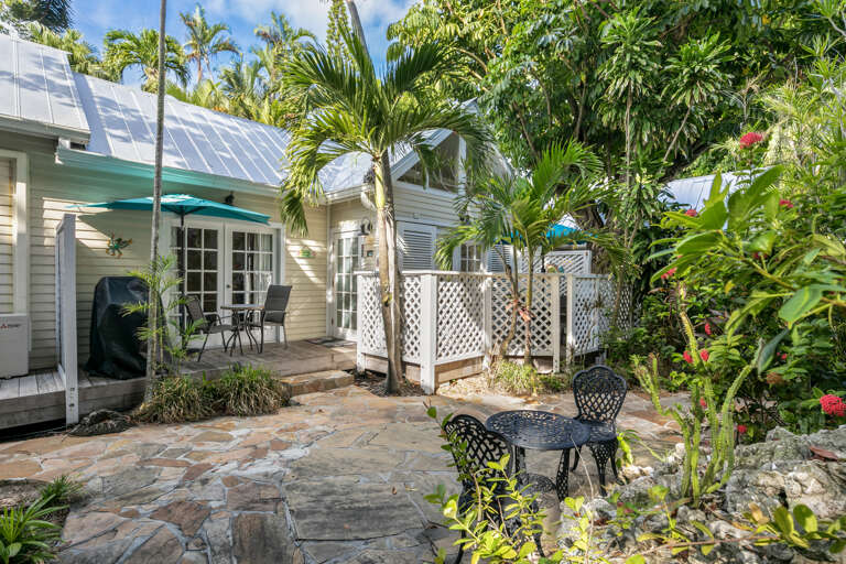 A charming coastal cottage nestled in lush tropical gardens, featuring a private patio where you can enjoy morning coffee surrounded by swaying palms and vibrant greenery.