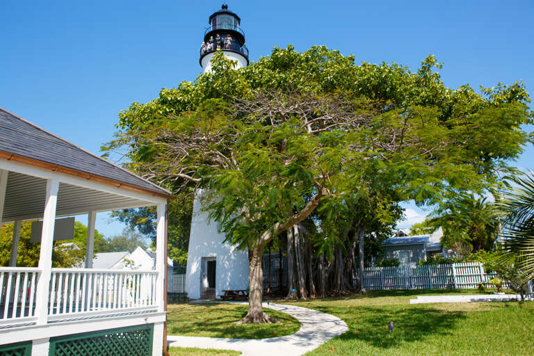 This historic lighthouse stands as a notable landmark near the property, surrounded by lush tropical trees and manicured grounds in a charming residential neighborhood.