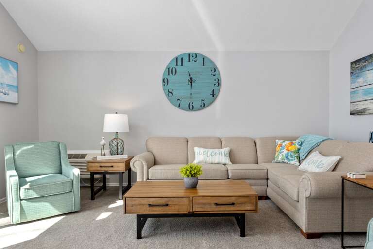 Light Living Room With Large Clock, Colorful Cushions, Wooden Furniture