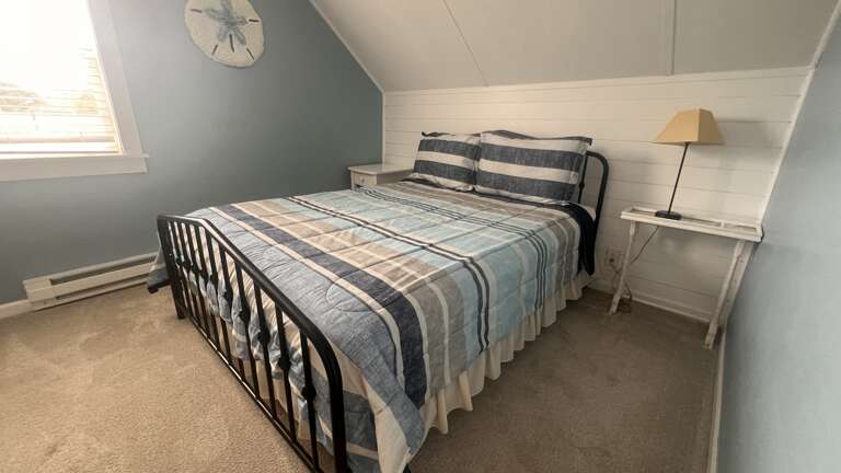 Cozy attic bedroom with plaid bedding and coastal touches creates your peaceful retreat under slanted ceilings.