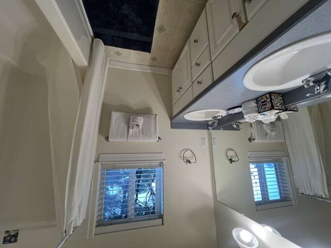 Relax in your private bathroom with dual sinks, fresh towels, and natural light streaming through shuttered windows—everything you need to feel refreshed and at home.