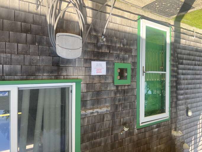 The property features weathered shingle siding accented with bright green trim around windows and doors, creating a distinctive coastal exterior.