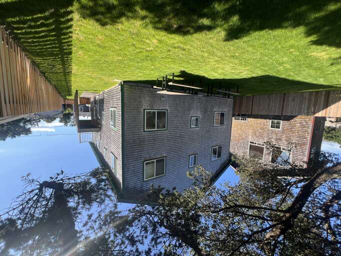 Aerial view showcasing the property's exterior and surrounding area, featuring expansive green lawn space and private backyard.
