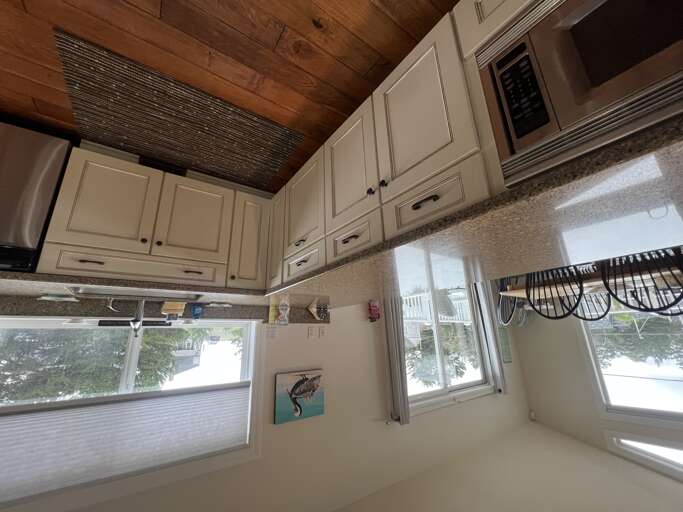 Your fully equipped kitchen blends modern convenience with rustic charm, featuring granite counters, white cabinetry, a microwave, and warm wood-beamed ceilings that make meal prep feel cozy.