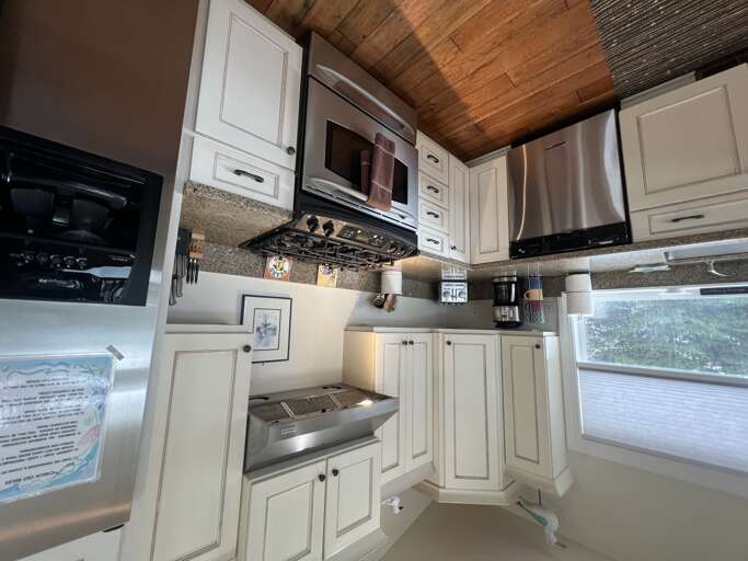 Your fully equipped kitchen features stainless steel appliances, granite countertops, and warm wood-paneled ceilings, making meal prep feel both modern and cozy.