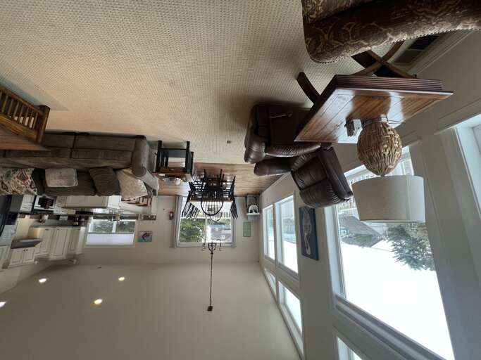 Spacious open-plan living area seamlessly connects the kitchen and living room, with inviting leather seating, polished floors, and abundant natural light to brighten your stay.