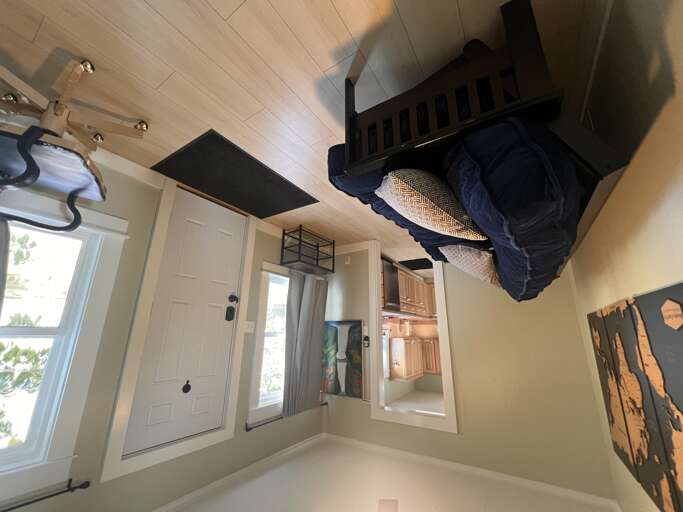 Bright, airy bedroom featuring a cozy loft-style sleeping area and stylish wood-paneled ceiling. Your personal retreat awaits with comfortable furnishings and natural light streaming through charming windows.