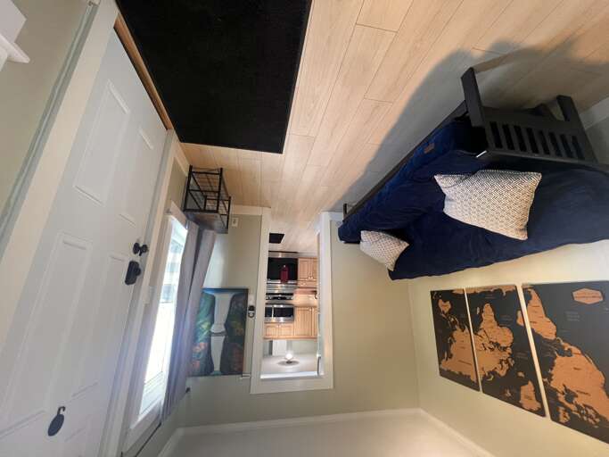 Your cozy bedroom awaits with a lofted bunk and soft linens, opening to a bright kitchenâperfect for restful nights and easy mornings in your home away from home.