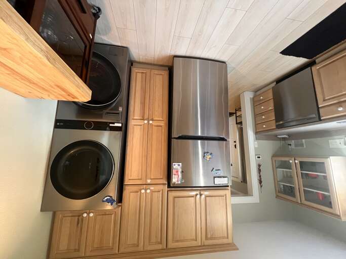 Modern kitchen with full-sized washer and dryer for your convenience, plus stainless steel appliances and warm wood cabinetry for comfortable living.
