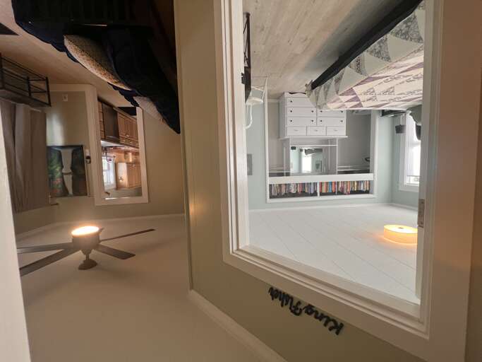 This unique interior showcases a modern loft-style design with exposed beams, white surfaces, and a creative upside-down perspective that adds architectural intrigue to the space.