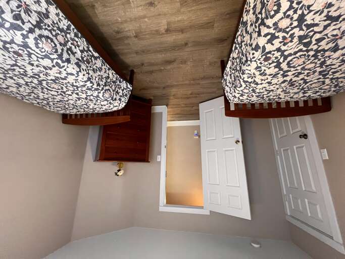 Two twin beds with charming blue damask bedding await you in this cozy bedroom, complete with warm wood-look flooring and a bedside table for your convenience.