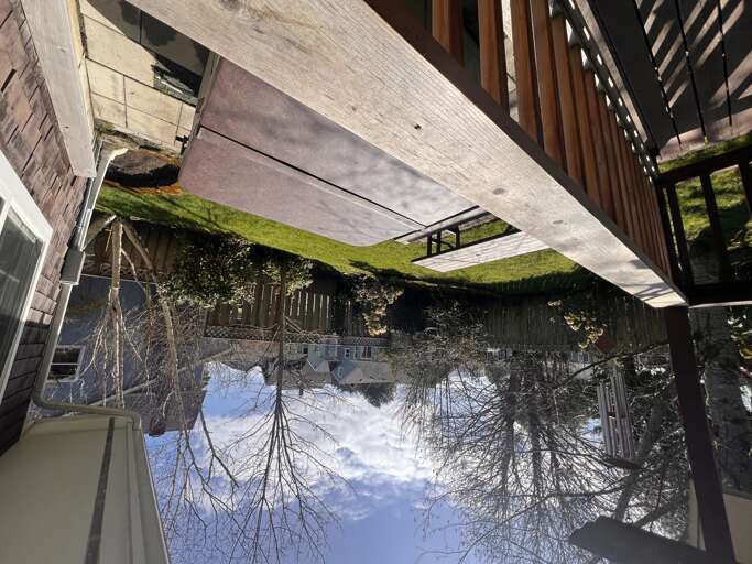 A charming wooden deck stretches over a peaceful pond, reflecting trees and sky—an inviting spot to enjoy tranquil surroundings and natural beauty during your stay.