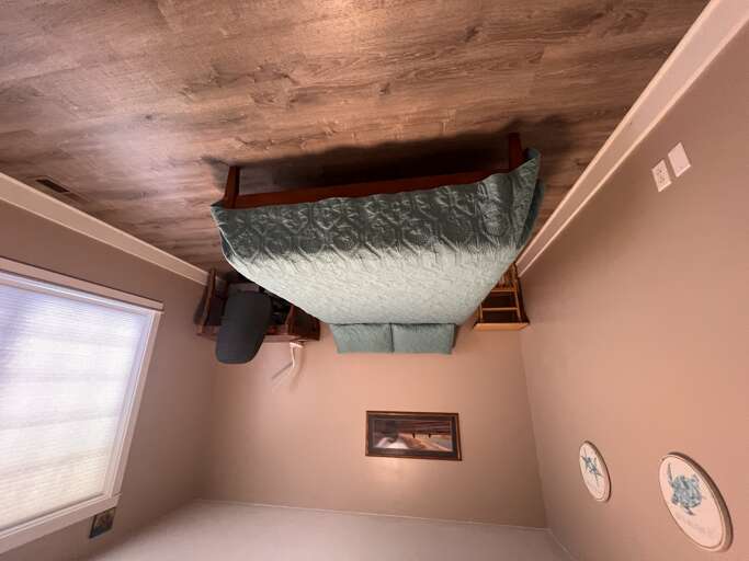 Your cozy bedroom features rustic wood-beamed ceilings, a plush queen bed with soft teal linens, and charming wall art for a peaceful retreat.