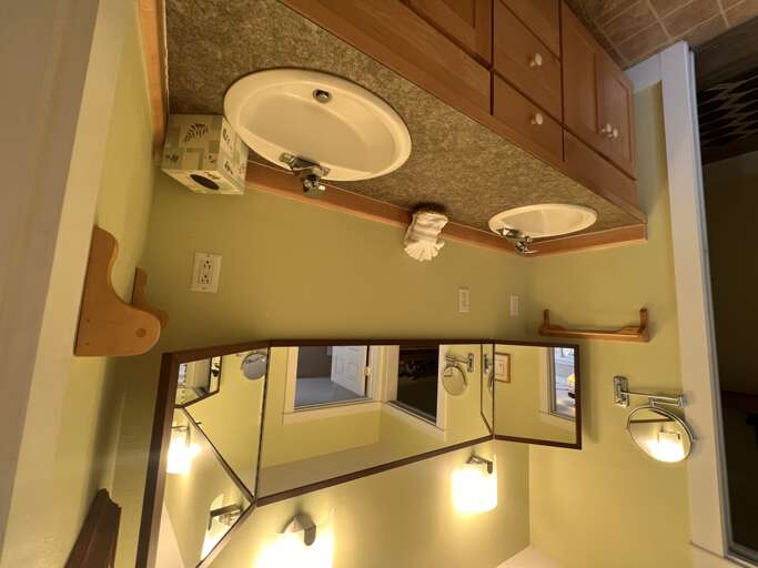 Refresh in your private bathroom featuring dual sinks with elegant granite countertops, warm wood cabinetry, and soft lighting that creates a calming start to your day.