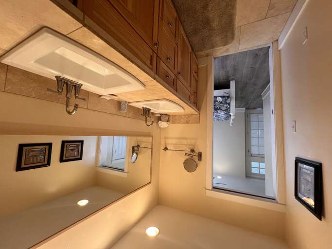 Step into your private oasis with a luxurious dual sink vanity, warm wood cabinetry, and soft ambient lighting that creates a spa-like atmosphere for your morning routine.