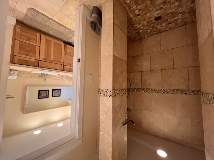 Step into your private spa-like retreat with elegant tilework, a soothing rain shower, and warm ambient lighting that invites you to unwind after exploring the area.