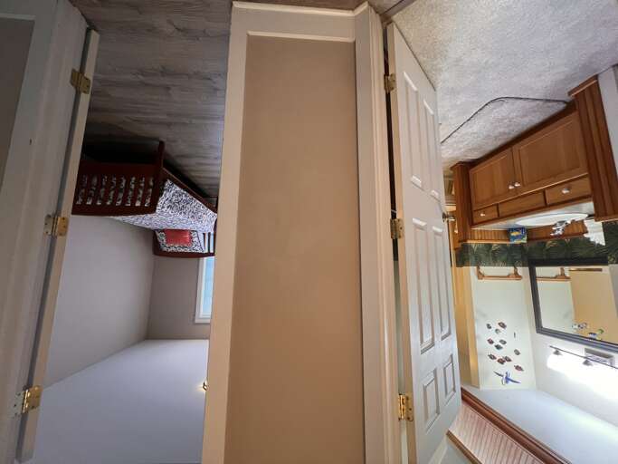 Step into your cozy space where every corner feels like home. The open door welcomes you to a well-appointed bedroom and a bright, inviting kitchen ready for your stay.