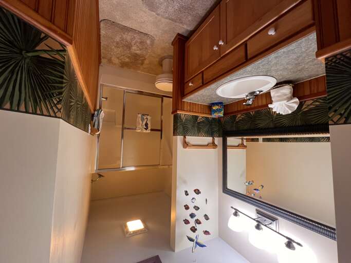 Step into your private bath, where warm wood cabinetry and tropical touches create a soothing, island-inspired retreat designed for your comfort.