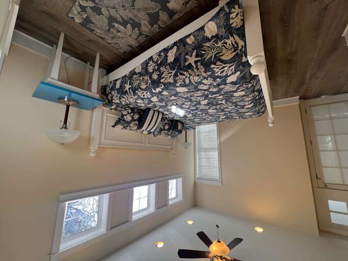 Curl up in this cozy sleeping loft with charming folk-art wallpaper and a plush bed draped in botanical linens. Natural light flows through cottage windows, creating your perfect retreat.