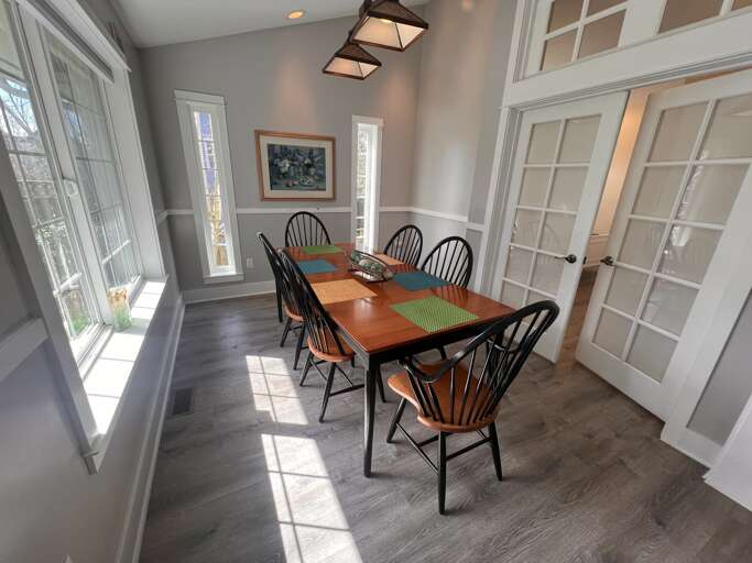 Gather around this warm dining space where natural light streams through tall windows, creating the perfect setting for your morning coffee or evening meals together.