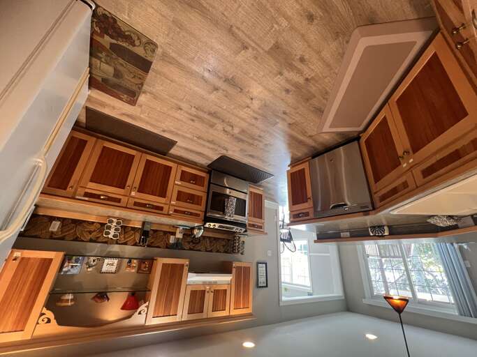 Step into your fully equipped kitchen where rustic wood cabinets meet modern appliances, and natural light pours in through charming windows. Cook, gather, and create memories under a beautifully textured ceiling that adds warmth to every meal.