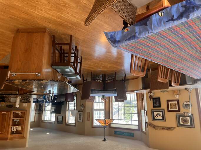 Step into your open-concept living space where rustic wood ceilings and charming décor create a warm, inviting atmosphere. Sunlight streams through large windows, highlighting the full kitchen and cozy seating areas perfect for your group getaway.