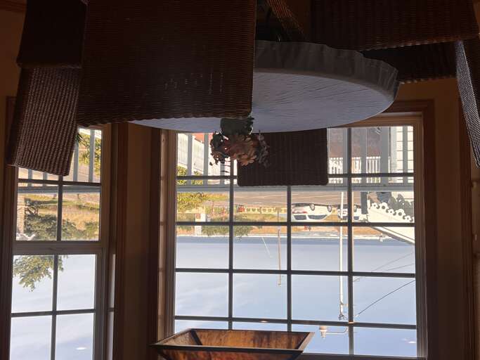 A charming dining nook bathed in natural light, where you can enjoy your morning coffee beneath rustic wicker pendant lights while looking out onto the quiet neighborhood.