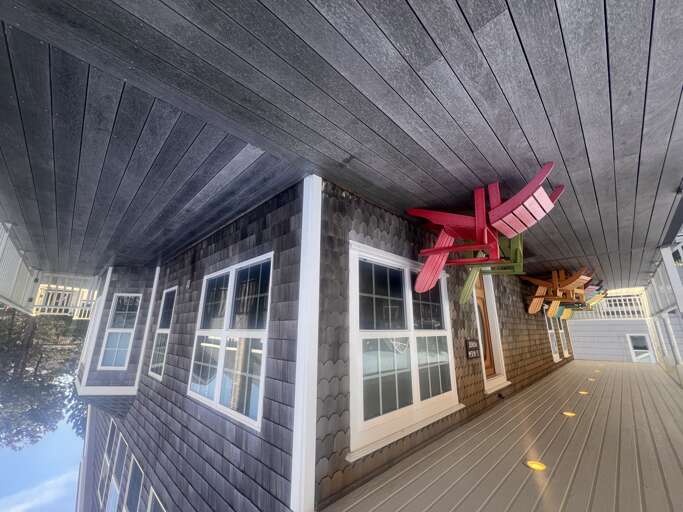 A covered outdoor deck features colorful custom beams overhead, creating a playful and unique architectural detail as part of the property's exterior living space.