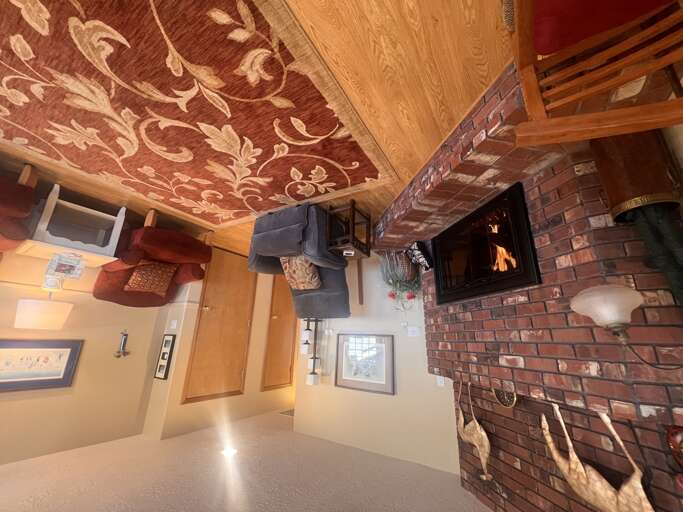 Warm wood tones and a charming brick fireplace create a cozy retreat where you can unwind after your adventures, wrapped in comfort and rustic elegance.