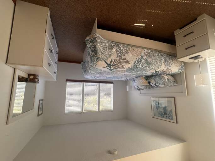 Relax in your cozy bedroom with crisp white linens and peaceful tropical prints. Natural light streams through blinds for your perfect morning awakening.